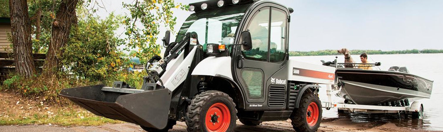 A Bobcat® utility vehicle towing a small boat out of the water